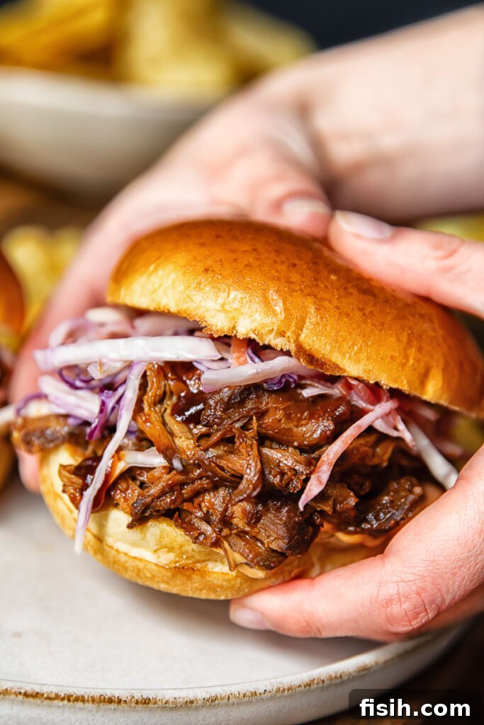 Pulled Pork Sandwich Delights 2 Close up shot of someone holding a pulled pork sandwich with fresh slaw