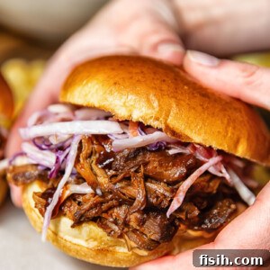 Pulled Pork Sandwich Delights 6 Close up shot of someone holding a pulled pork sandwich with fresh slaw