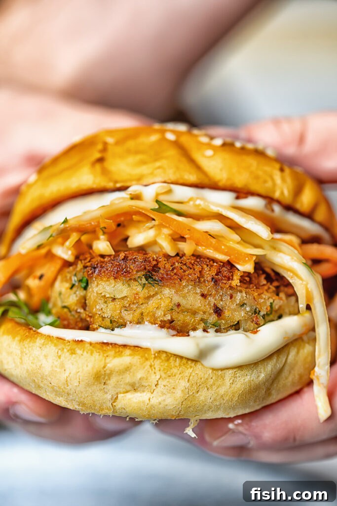 Close up shot of the side of a crab cake in a brioche bun with coleslaw and garlic aioli