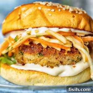 Side shot of crab cake sandwich on a plate with garlic aioli and coleslaw