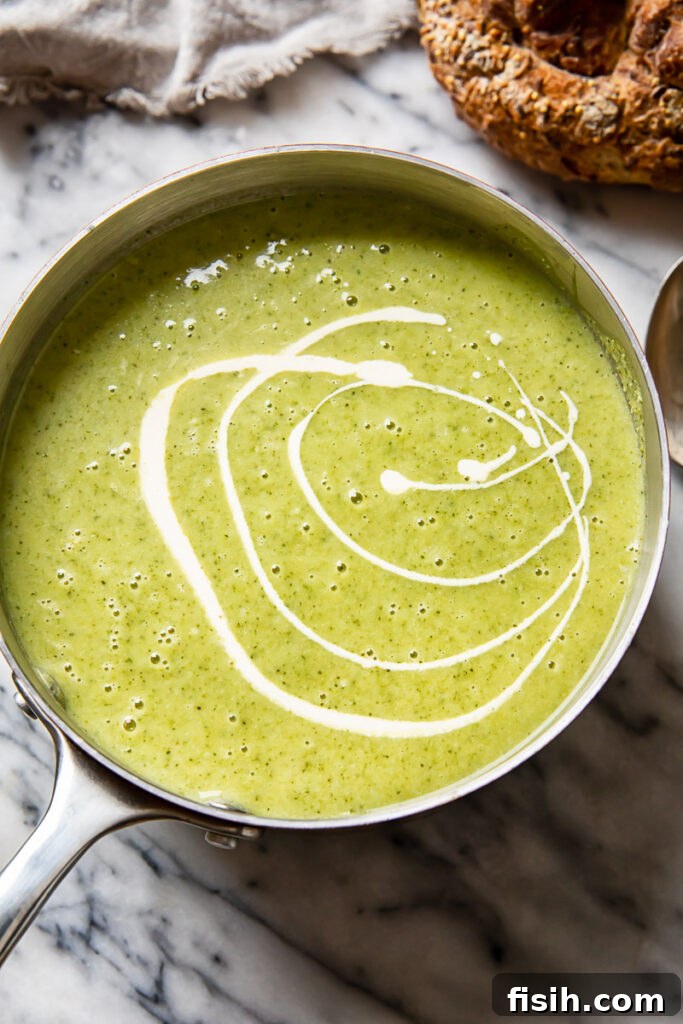 A small cooking pot filled with the bubbling, creamy mixture of broccoli and cauliflower soup, ready for blending.