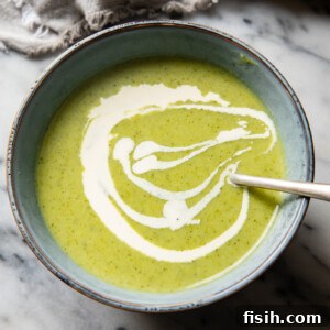 A beautifully presented bowl of creamy broccoli and cauliflower soup, garnished with a swirl of cream, highlighting its inviting texture.