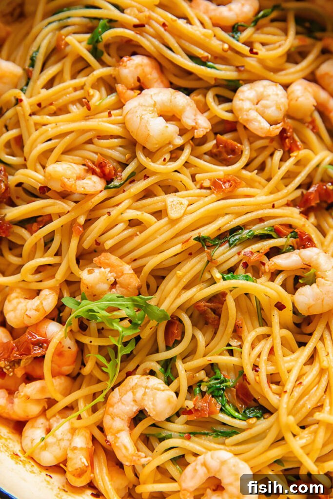 Sun-Drenched Tomato & Chili Shrimp Spaghetti with Arugula 2 A close-up of a perfectly plated dish of sun-dried tomato and chili spaghetti with shrimp, garnished with fresh arugula, ready to be enjoyed.