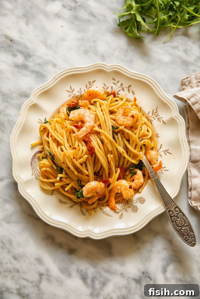 Sun-Drenched Tomato & Chili Shrimp Spaghetti with Arugula 3 An overhead view of a fork twirling a generous portion of sun-dried tomato spaghetti, highlighting the rich colors and inviting texture of the dish.
