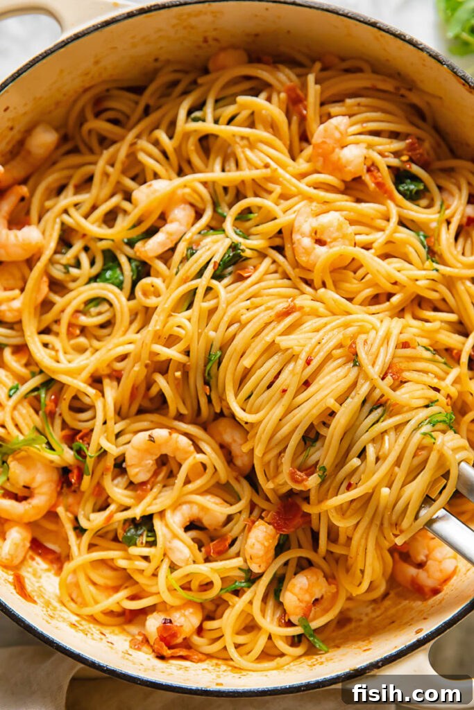 Sun-Drenched Tomato & Chili Shrimp Spaghetti with Arugula 4 A vibrant aerial shot of sun-dried tomato pasta simmering in a pan, adorned with plump shrimp, fiery chili flakes, and fresh arugula, creating an irresistible aroma.