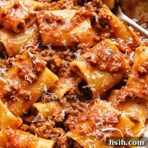 Close up shot of paccheri pasta in beef and tomato sauce with nduja and topped with Parmesan cheese