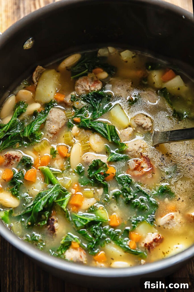 Rustic Sausage and White Bean Comfort 2 Close up shot of white bean and sausage soup in a pot with potatoes, carrot and celery