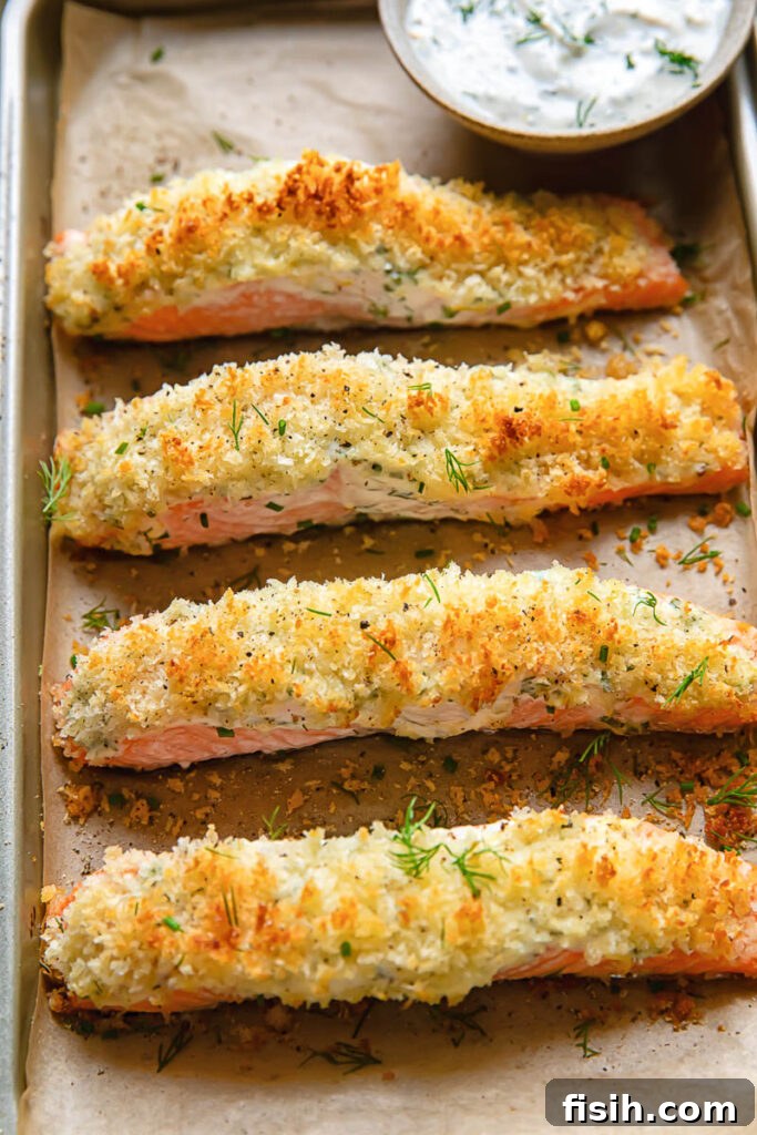 Top down shot of garlic baked salmon fillets on a baking sheet with a bowl of garlic dip