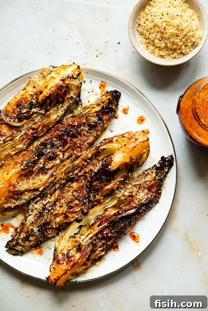 Gochujang roasted cabbage on a plate next to a bowl of breadcrumbs