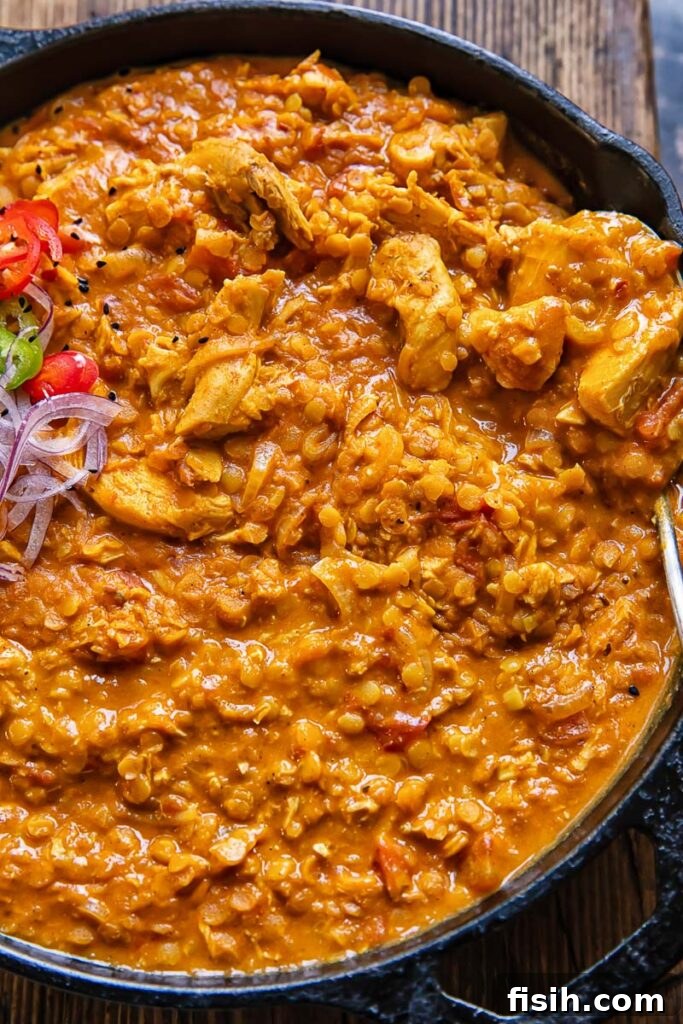 Top down shot of hearty turkey and lentil curry in a wide pan, garnished with fresh herbs