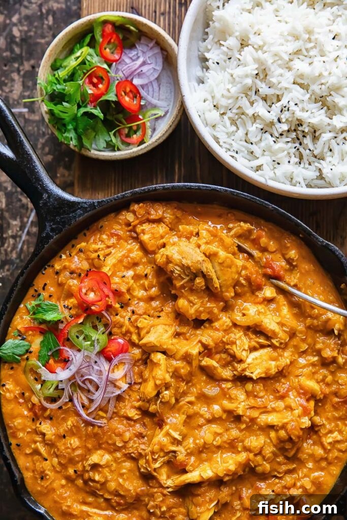 Pan with vibrant turkey and lentil curry next to a serving of white rice