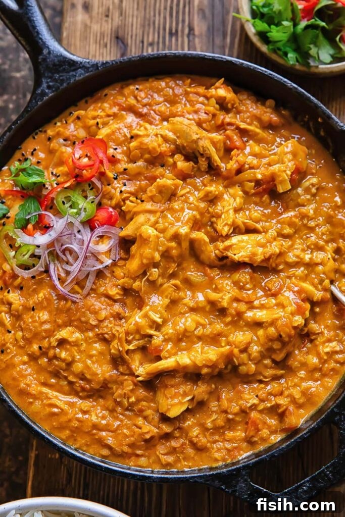 Close up shot of rich leftover turkey curry in a pan, beautifully topped with freshly sliced red onion and vibrant coriander