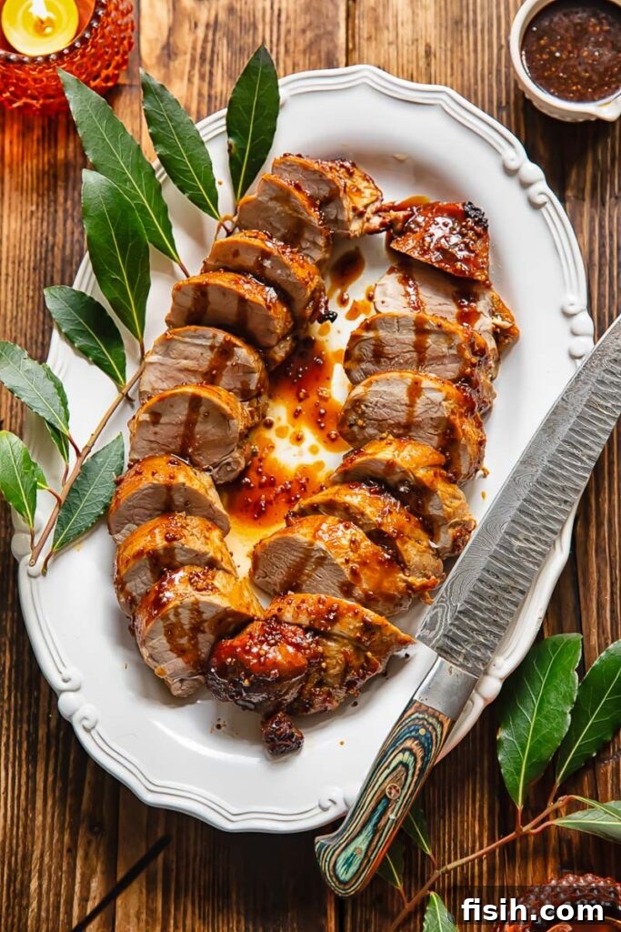 Perfectly sliced pork tenderloin medallions, showcasing the juicy interior, neatly lined on an oval serving plate.