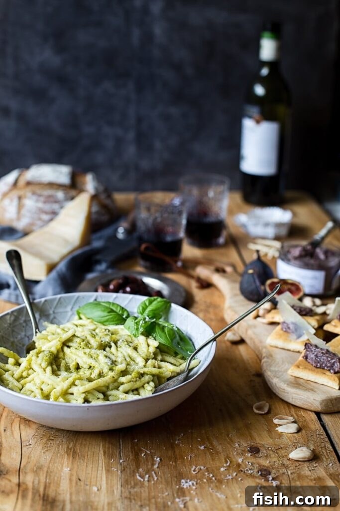 Bowl of pasta with cheese board and wine bottle in the background