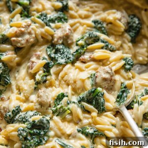 Close up shot of italian sausage and kale orzo with a spoon