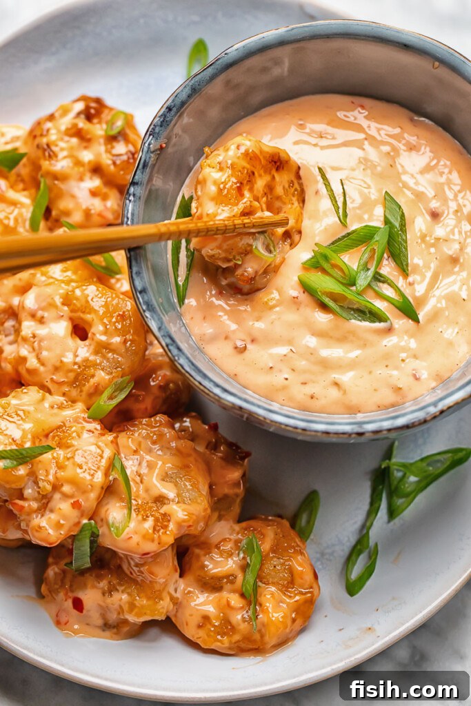 Close up shot of bang bang shrimp being dipped in spice mayo
