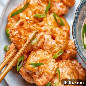 Close up shot of bang bang shrimp being picked up from a plate with chop sticks
