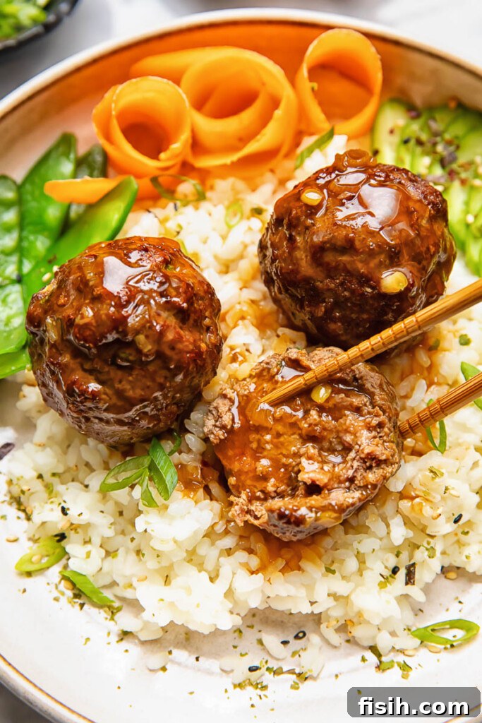 Close up shot of teriyaki meatballs served on top of a bowl of rice