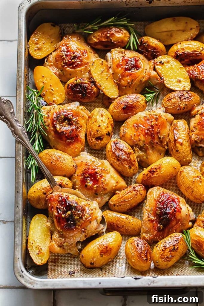 One Pan Honey Mustard Chicken and Potatoes 3 Top down shot of honey mustard chicken thighs with a serving spoon in a baking tray