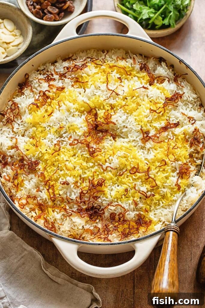 Effortless Chicken Biryani 3 Top down shot of fragrant basmati rice layered with spices, golden fried onions, and toasted almonds, prepared for chicken biryani.