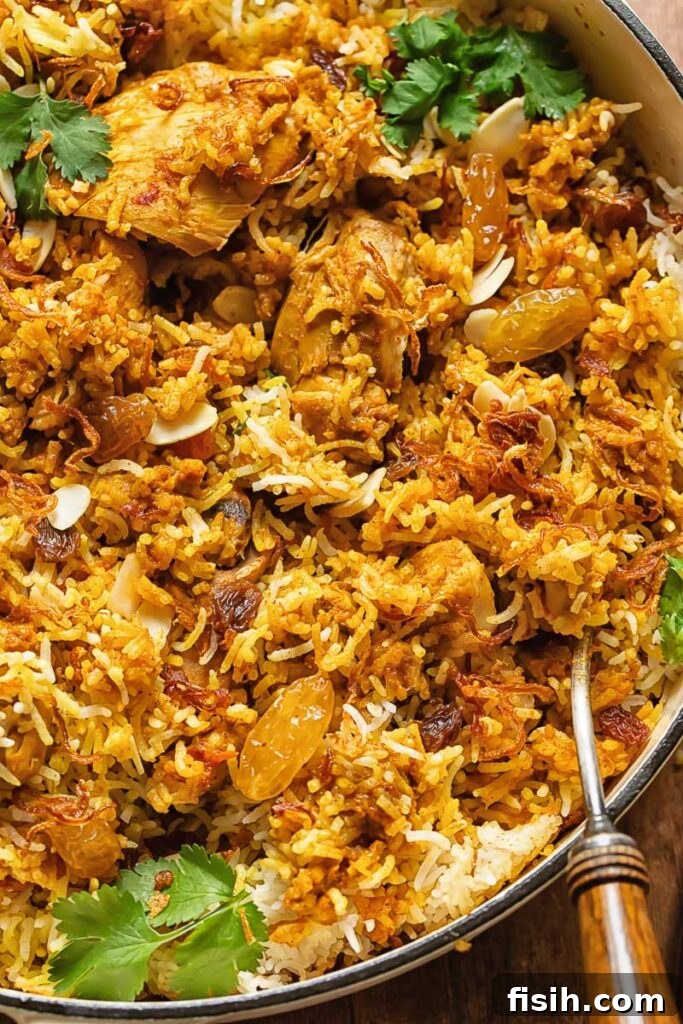 Effortless Chicken Biryani 4 Close up shot of aromatic chicken biryani in a large pot with a serving spoon, highlighting the perfectly cooked layers of rice and chicken.