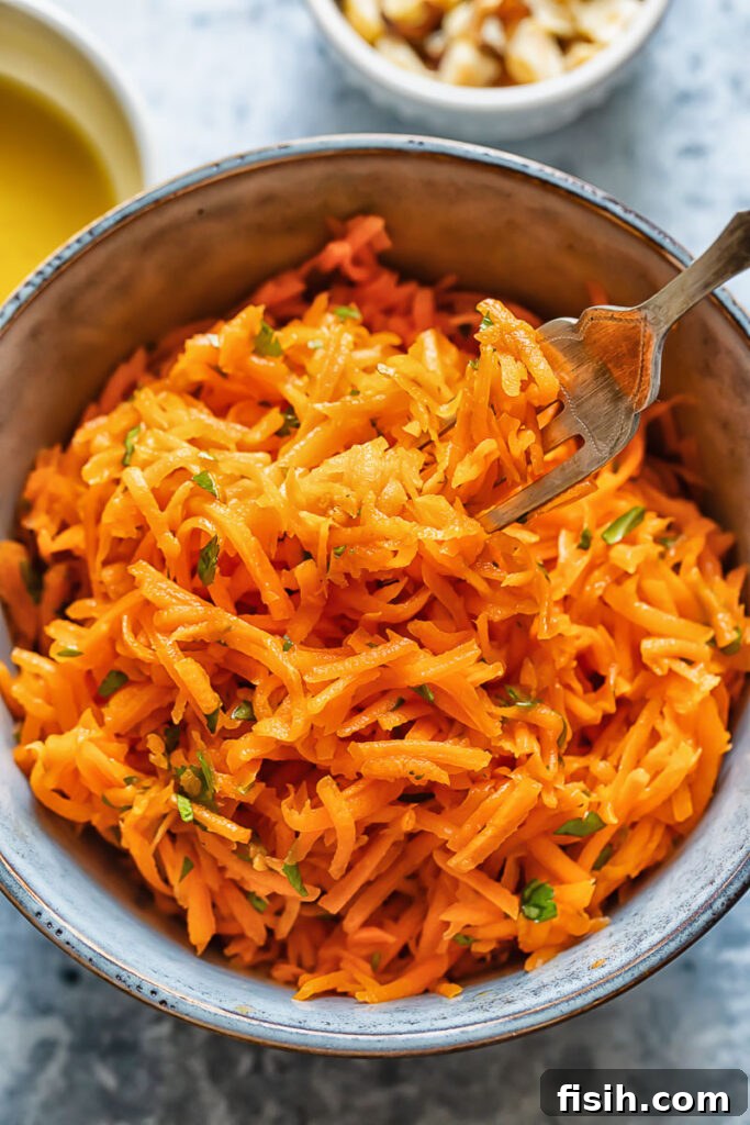Vibrant French Carrot Salad with Toasted Hazelnut Crumble 3 Close up shot of a bowl of french carrot salad with a fork