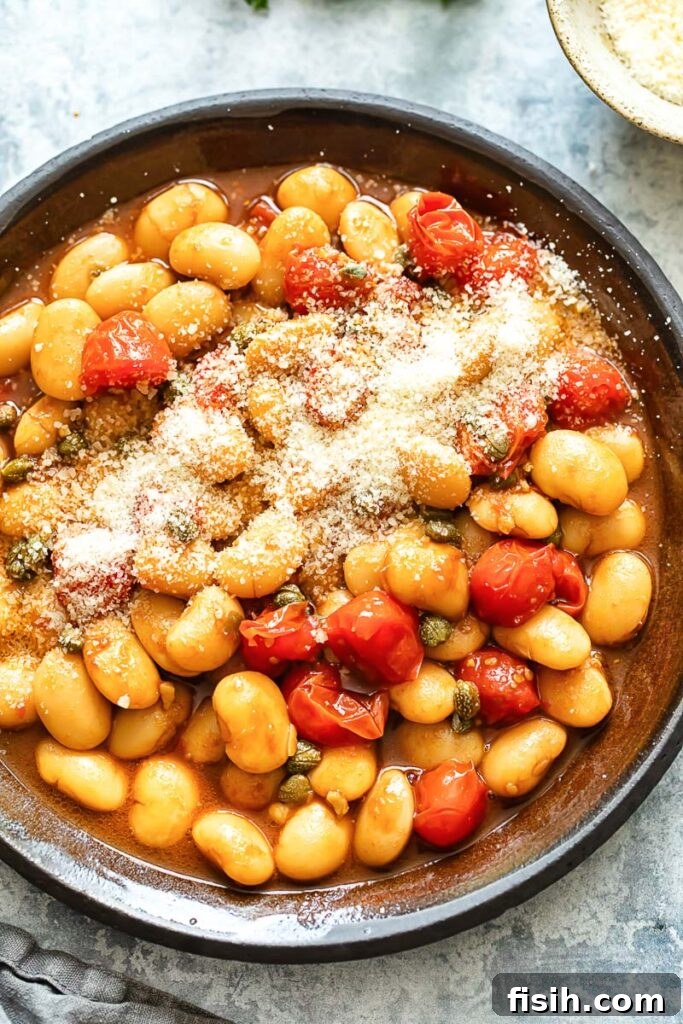 Creamy Butter Beans with Balsamic Burst Tomatoes 2 A top-down shot of vibrant butter beans in a glossy cherry tomato sauce, served in a rustic pan, ready to be enjoyed.