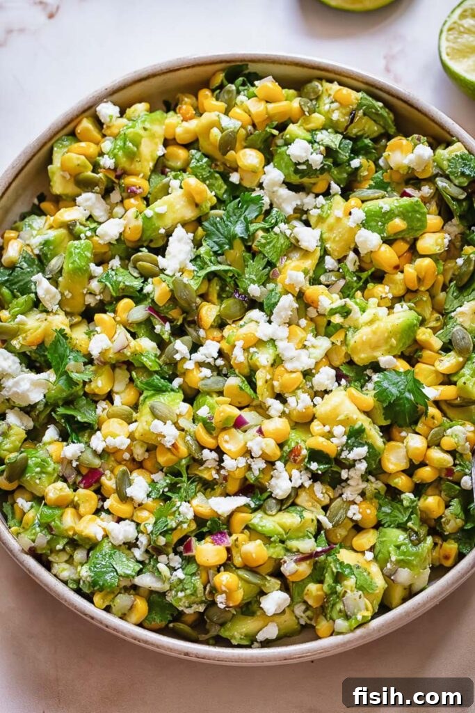 Top down shot of avocado and corn salad in a wide bowl, garnished with fresh cilantro and cheese.