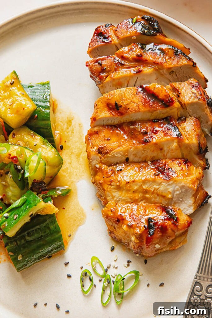 Sliced teriyaki pork chop next to a cucumber salad