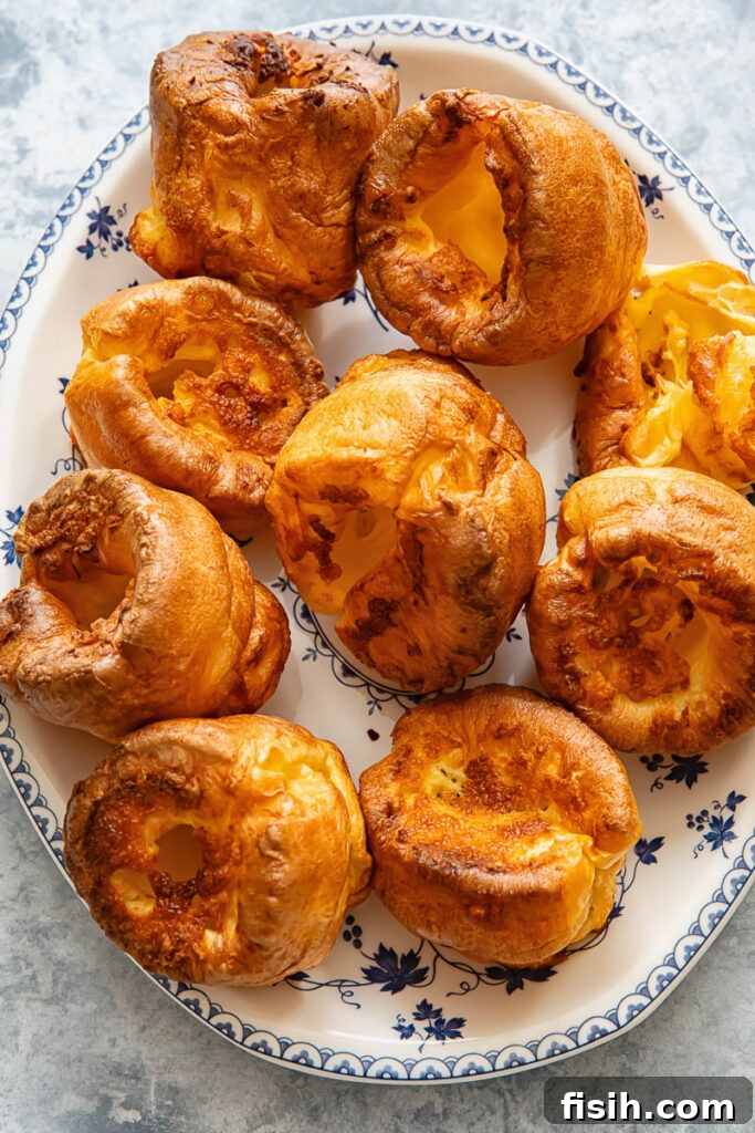 Top down shot of golden, perfectly risen Yorkshire puddings on a platter, ready to be served with a roast dinner.