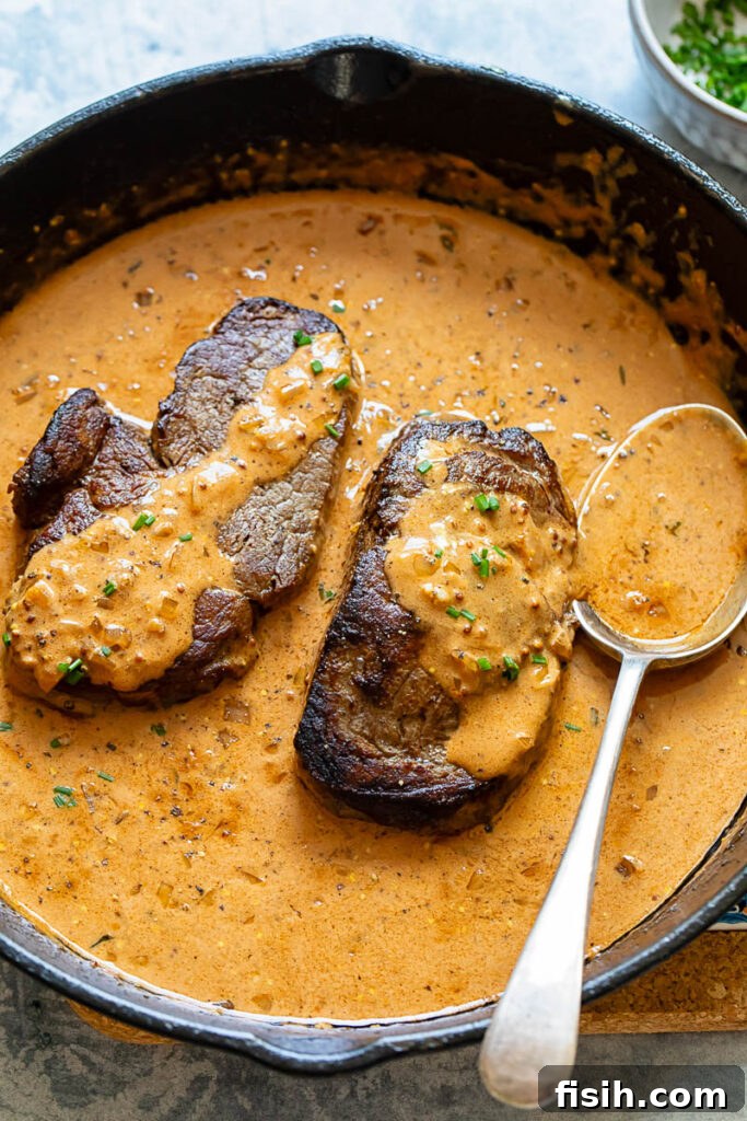 Steak Diane fillets in a cast iron pan with a spoon