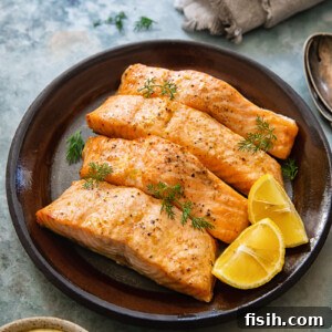 Top-down view of perfectly cooked Air Fryer Salmon with a vibrant lemon dill sauce and a slice of lemon.