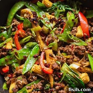 Top-down shot of a colorful ground beef stir fry brimming with bright vegetables in a large pan.