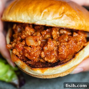 Close up shot of someone holding a smoky sloppy joe in a bun.