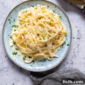 Overhead shot of pasta with a luscious cream sauce, garnished with fresh herbs.