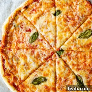 Top-down view of a golden, flaky puff pastry pizza margherita on a baking tray.