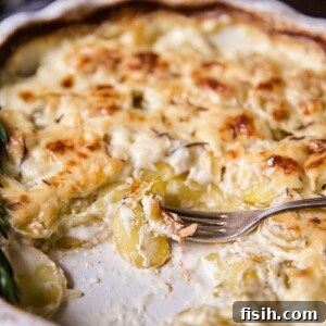 A rustic baking dish filled with golden-brown Rosemary Potatoes au Gratin, showcasing tender potato slices baked in a rich, creamy sauce. An elegant and aromatic potato side dish.