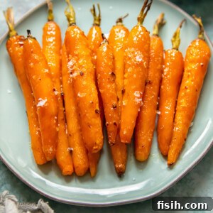 Vibrantly orange Maple Glazed Roasted Carrots arranged artfully on a blue plate, showcasing their tender texture and shiny, caramelized glaze. A simple yet elegant vegetable side.