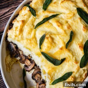 Mashed Potato Casserole with a visible, savory middle layer of sautéed mushrooms and caramelized onions, baked to a tempting golden-brown finish. An indulgent and flavorful potato side.
