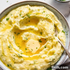 Creamy Herb and Garlic Mashed Potatoes with a tempting pool of melted butter in the center, garnished with vibrant fresh herbs. A flavorful and aromatic twist on classic mashed potatoes.