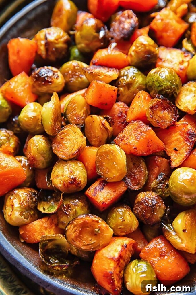 Close-up of roasted Brussels sprouts and sweet potatoes mixed in a large serving bowl, highlighting their textured surfaces.
