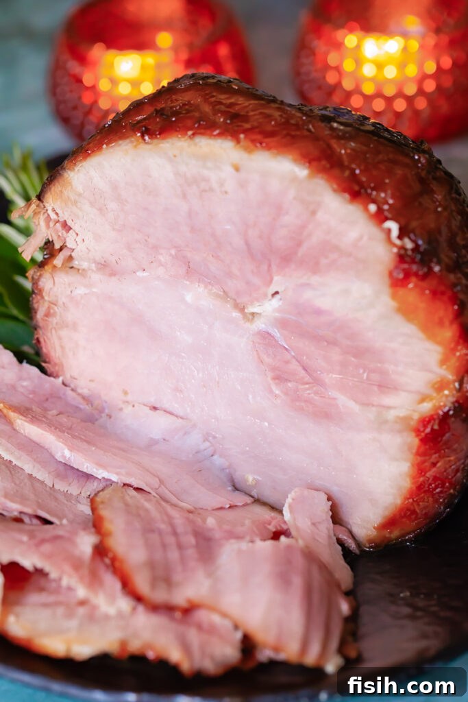 Sticky Sweet Bourbon Maple Ham 4 a glazed ham with pieces cut and a festive table in the background