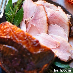 slices of glazed ham shown from the top down in a festive setting, with the glazed ham in the foreground