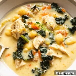 Creamy chicken gnocchi soup served in a warm-toned bowl with a spoon, showing tender gnocchi, chicken, and a rich, thick broth.