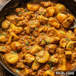 Top down view of a comforting chicken curry in a pan with tender potatoes.