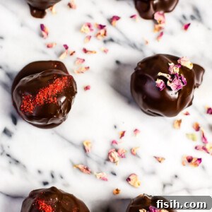 An inviting top-down view of six rich chocolate cake truffles, artfully dusted with cocoa powder and freeze-dried strawberries.