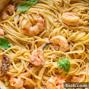 Linguine pasta in a pot, generously topped with plump marry me shrimp in a creamy sun-dried tomato sauce and fresh basil leaves.