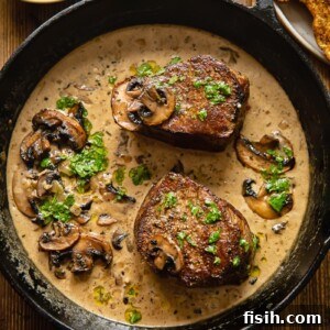 Two perfectly seared filet mignon steaks in a cast iron pan, glistening with a rich mushroom Marsala sauce.