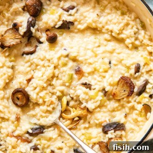 A bowl of creamy truffle risotto, garnished with fresh herbs and shaved parmesan, with a spoon ready to serve.