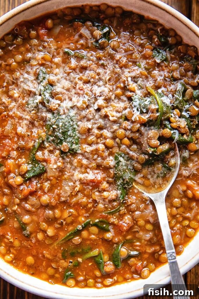 Top down view of a large bowl of homemade lentil and spinach soup, garnished with fresh herbs, ready to be served.